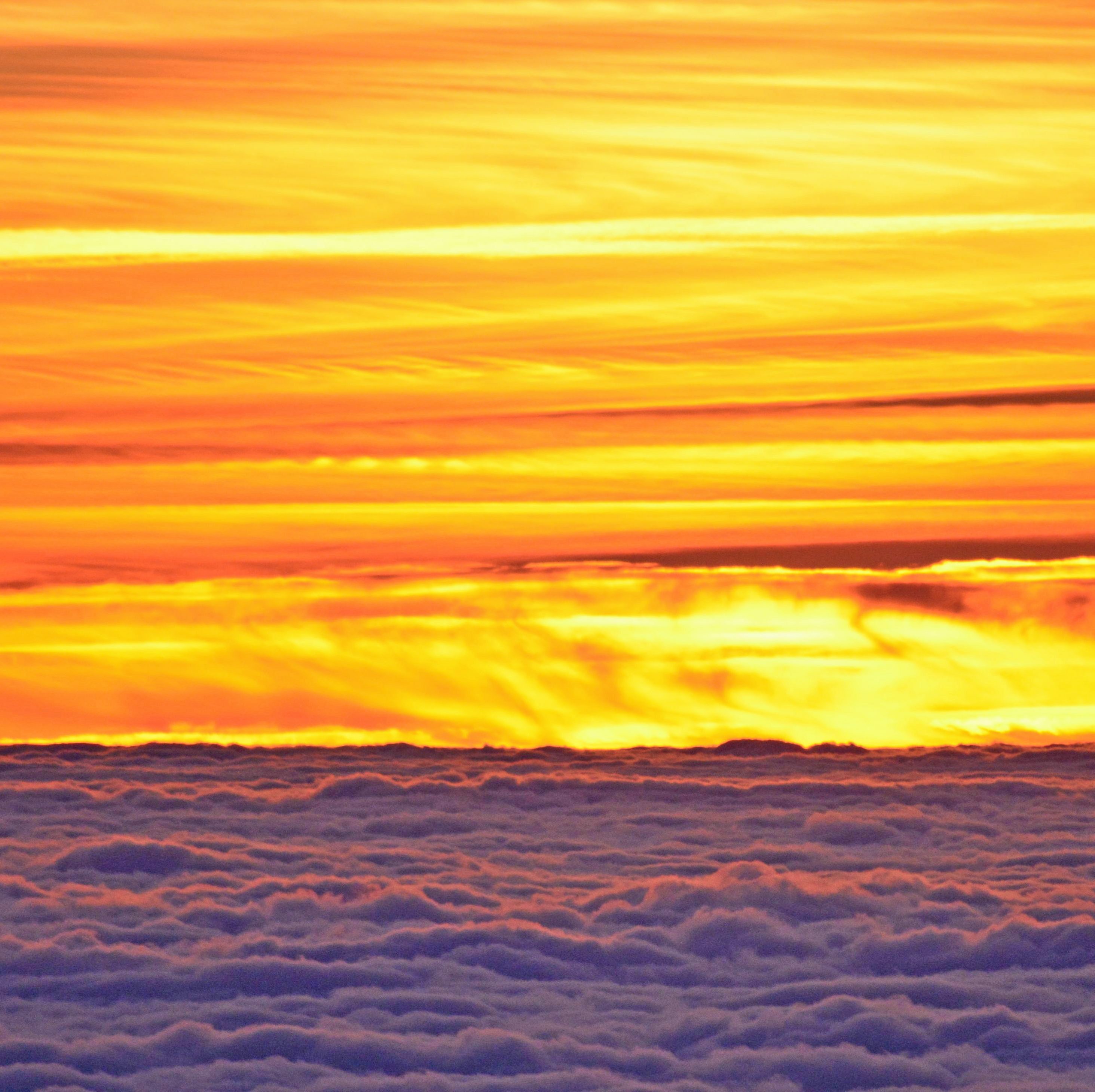 A fiery sky at sunset, taken from above the cloud line.